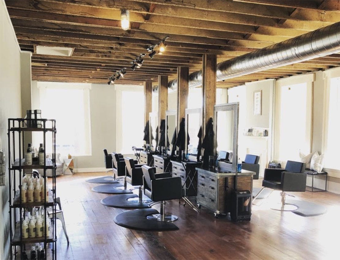 barber shop interior with four double-sided barber stations, natural light and retail display shelves