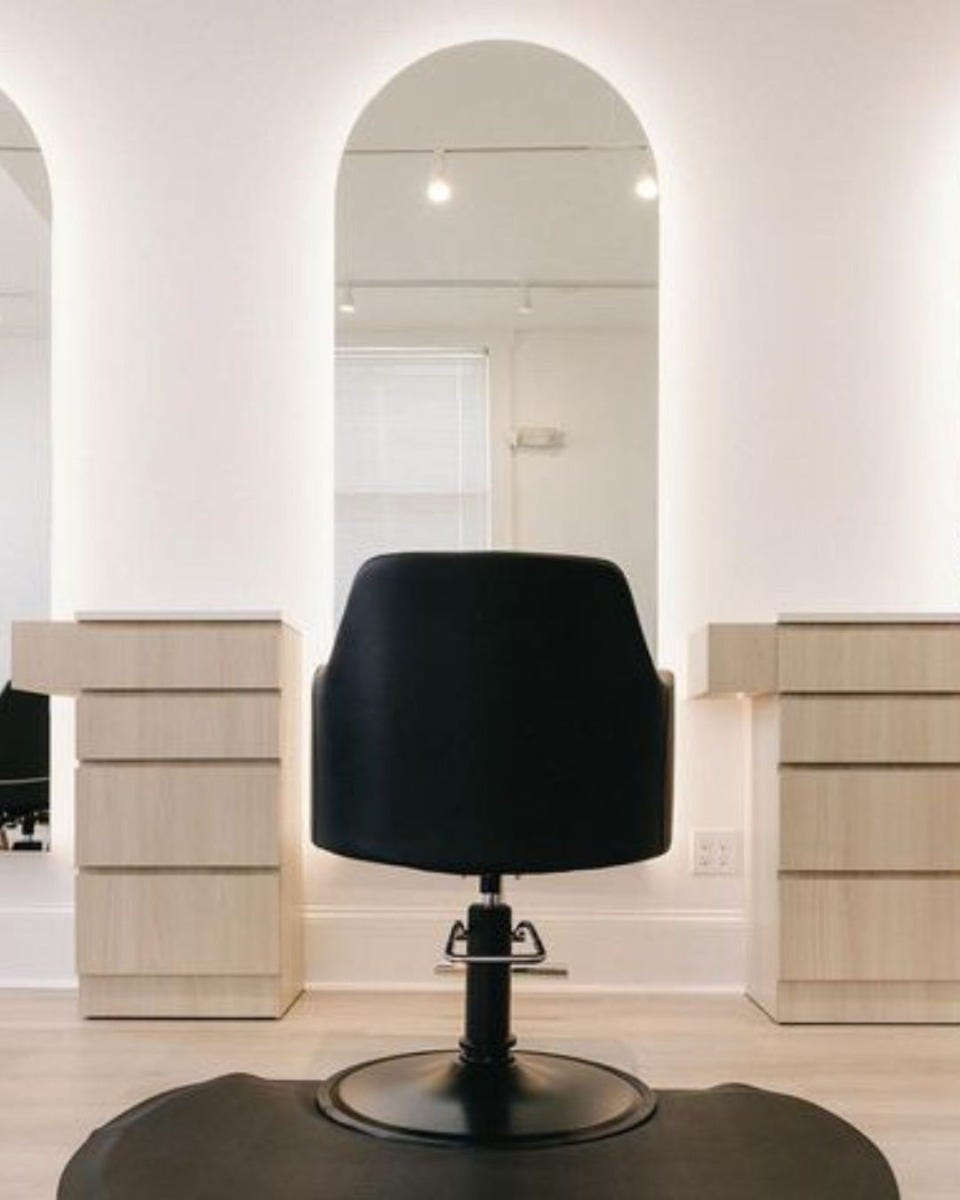 salon styling station with black chair and large arched LED mirror